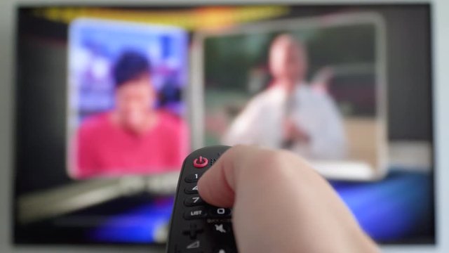Channel surfing, focused on the hand and remote control. Internet Connected TV. Male hand holding the TV remote control