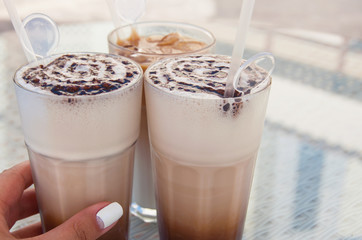 Iced coffee cocktail with ice. Summer conception. Refreshment beverages. Delicious latte. Hand hold the glass