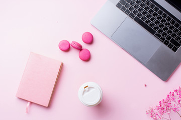 Flatlay with laptop, coffee and macarons on pink background. Top view, copy space. Workplace concept.