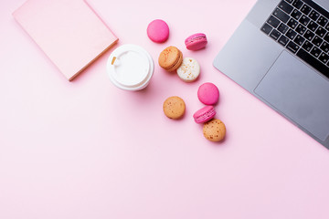Fototapeta na wymiar Flatlay with laptop, coffee and macarons on pink background. Top view, copy space. Workplace concept.