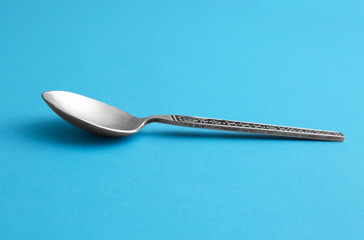 Clean empty vintage tea spoon on blue background
