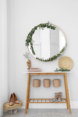 Round mirror and table with accessories near white wall. Modern interior design