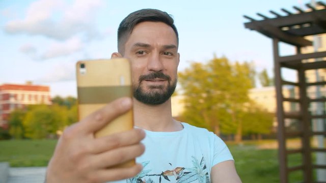 Portrait of smiling man shooting selfie while spinning on blurred background