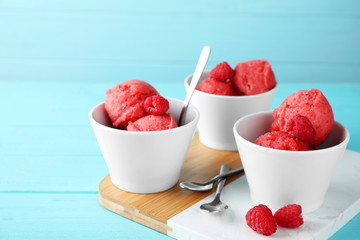 Bowls with delicious raspberry ice cream on light blue wooden table