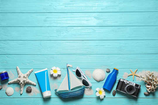 Flat lay composition with stylish beach accessories on light blue wooden background, space for text