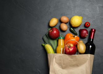 Paper bag with groceries on grey background, flat lay