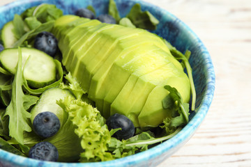 Delicious avocado salad with blueberries in bowl on table, closeup