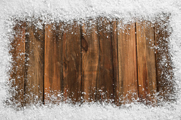 Obraz na płótnie Canvas Frame of white snow on wooden background, top view with space for text. Christmas season