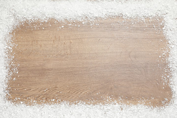 Frame of white snow and space for text on wooden background, top view. Christmas season
