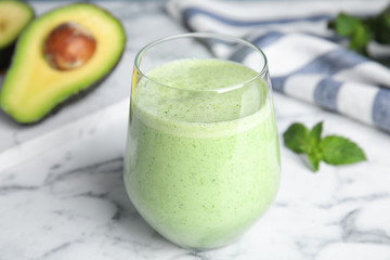 Glass of tasty avocado smoothie on marble table
