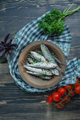 Baltic herring seafood. Salted herring fish in a bowl with spices and herbs. Wood background.