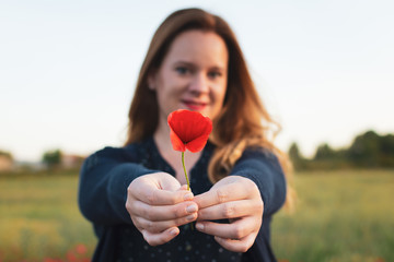 Selective focus of a beautiful woman holding a red poppies flower.