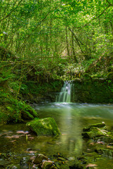 Sun ray lights over a small waterfall in a river in Galdames, Basque Country, Spain