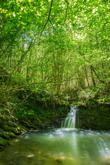 Obraz premium Sun ray lights over a small waterfall in a river in Galdames, Basque Country, Spain