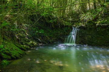 Sun ray lights over a small waterfall in a river in Galdames, Basque Country, Spain