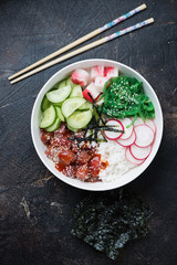 White bowl with ahi poke, flatlay over dark brown stone surface, vertical shot