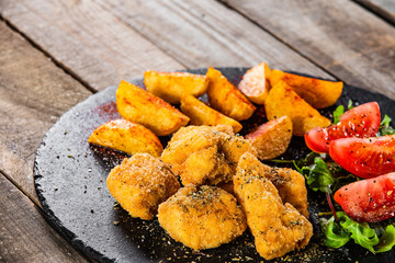 Fried chicken nuggets, baked potatoes and vegetable salad