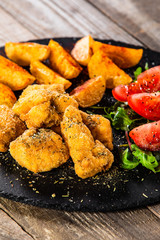 Fried chicken nuggets, baked potatoes and vegetable salad