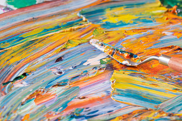 Obraz na płótnie Canvas Bright, juicy, multi-colored abstraction of their mixing of oil paints on a palette close-up.
