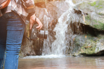 A women Walking with jeans and sneaker shoes and Waterfall background, concept travel, soft and select focus.