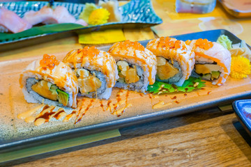 Salmon cheese, california roll topping with cheese and avocado, shoyu soy sauce and salmon eggs lay on plate. Salmon sushi roll, Japanese food. (selective focus point)