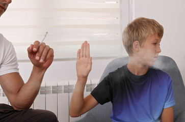 Stop smoking near children. Father smoking cigarette , boy disgusted by smoke