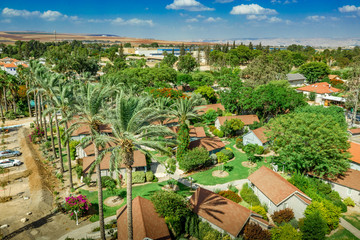 Aerial view of the vacation rental bungalows, houses at the popular Israeli destination kibbutz Nir David, with gorgeous palm trees and red roofs under the blue summer sky
