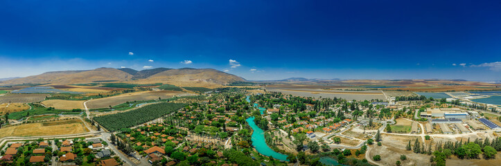 Aerial panorama view of Kibbutz Nir David in Northern Israel with the turquoise color Amal river and the surrounding agricultural land  