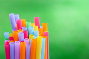 Obraz premium Multiple color drinking straws on a green grass background blur