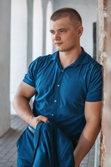 Young handsome sporty man in a blue business suit on a background of a brick wall in the summer.
