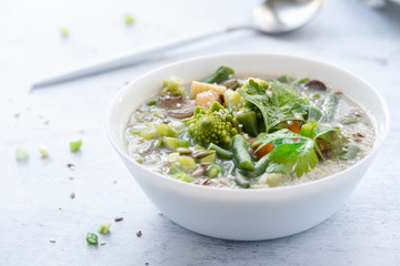 Vegetarian vegetable soup with quinoa and sesame seeds in a white bowl on the table. Tasty vegan soup, healthy eating concept.