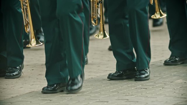 A wind instrument parade - people in green costumes marching on the point holding musical instruments - military musical festival