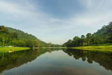 Obraz premium Water reservoir has green forests and mountains in background with blue sky at Sam Lan National Park, Saraburi, Thailand
