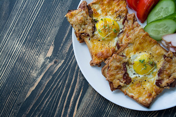 Grilled sandwich with egg, vegetables and bacon on a dark wooden background. Tasty breakfast.