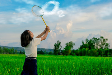 A happy girl enjoying nature in meadow. Outstretched arms, breathing fresh air with a cloudy blue sky in the background - concept of clean atmosphere.