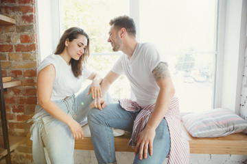 Romantic. Young couple moved to a new house or apartment. Look happy and confident. Family, moving, relations, first home concept. Sitting near by window and relaxing after unpacking and cleaning.