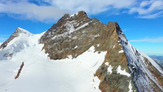Aerial, drone shot, towards snowy, Jungfrau mountain summit, at Jungfraujoch, the top of Europe, on a sunny, day, in Bernese Alps of Switzerland