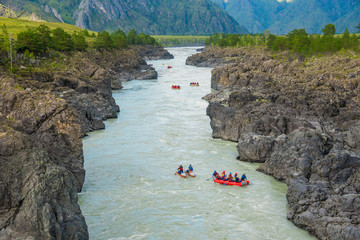 A lot of rafts and kayaks floating down a mountain river Katun. Mountain landscape, Altai mountains, Russia.