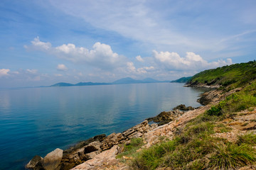 Fototapeta premium sea horizon with rocky shore cliffs and sun light blue sky background. Sea waves crashing on rocks, Samed, Thailand