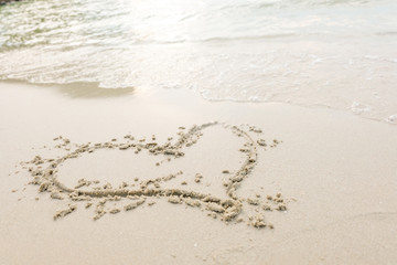Heart drawn on a sand of beach with the wave of the sea in the bright sunlight, Romantic love background.