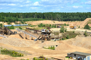 View on the mining quarry for the production of crushed stone, sand and gravel. Crusher plant with belt conveyor, crushing process, grinding stone. Work in open-pit mine
