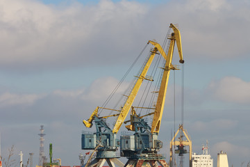 Fototapeta na wymiar Working cranes in a small port in sunny weather.