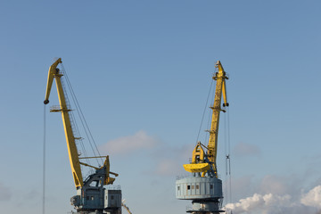 Fototapeta na wymiar Working cranes in a small port in sunny weather.