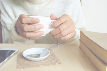 Relaxing moments , Cup of coffee and a book on wooden table in nature background, color of vintage tone and soft focus, winter morning concept.