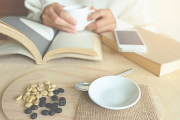 Relaxing moments , Cup of coffee and a book on wooden table in nature background, color of vintage tone and soft focus, winter morning concept.