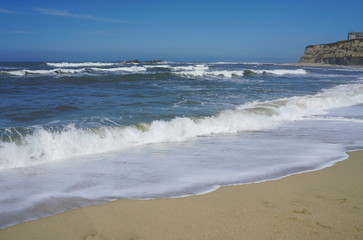 Fototapeta na wymiar Blue sky, white ocean waves and sunshine sandy beach at Pacific Coast, California