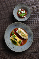 Fine dining, white fish fillet breaded in herbs and spice with homemade ravioli and tomato sauce