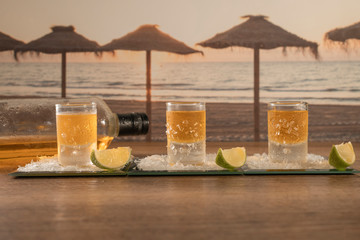 Three shots of rum served on a tray with lots of salt and slices of lime on a wooden table. Luxurious and Tasty Mexican Rum