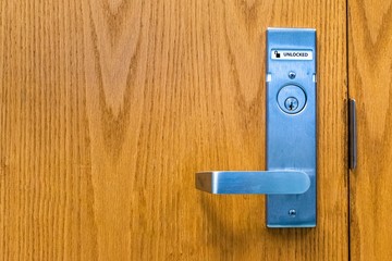 Horizontal landscape photo of a door lock and handle in the unlocked position with the word unlocked displayed. Picture displays a single door with no seam or latch.