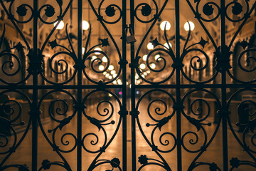 Fototapeta na wymiar Beautiful closed wrought-iron gates, evening, night, light of lanterns. Central Market Square Krakow, Poland